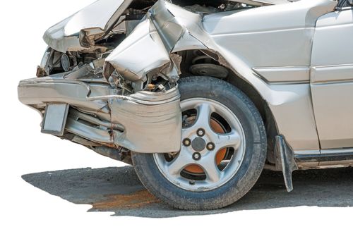 Rear end of a silver car badly damaged in a crash, with crushed bumper and bent wheel area