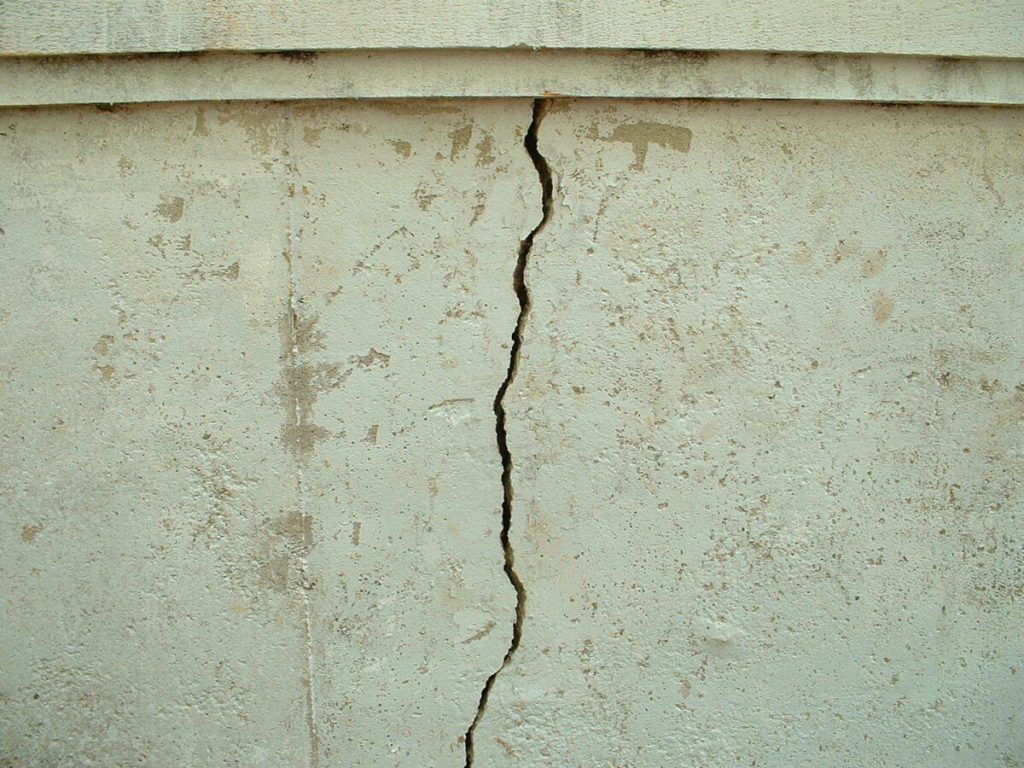 Vertical crack in a light gray concrete wall.