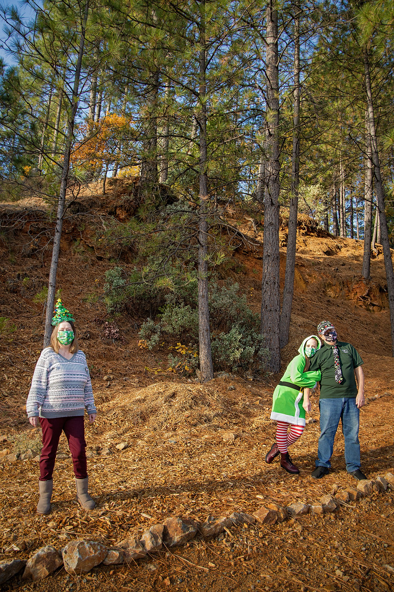 3 individuals posing for the camera with the forest as their background