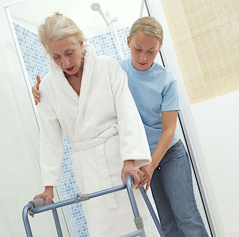 A nurse is helping an elderly man with a walker.