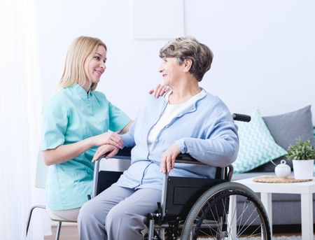 A nurse is talking to an elderly woman in a wheelchair.