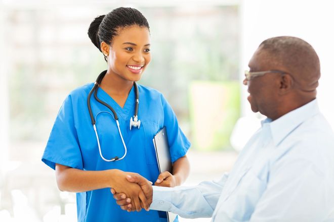 A nurse is shaking hands with a patient in a hospital.