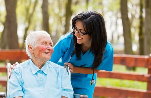 A nurse is talking to an elderly woman in a wheelchair.