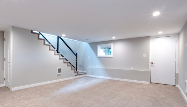 An empty basement with a staircase and a window.