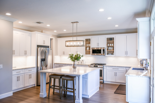 A kitchen with white cabinets , stainless steel appliances , and a large island.