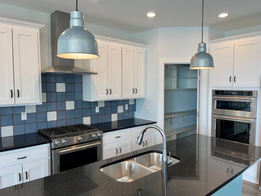 A kitchen with white cabinets , stainless steel appliances , a sink and a stove.