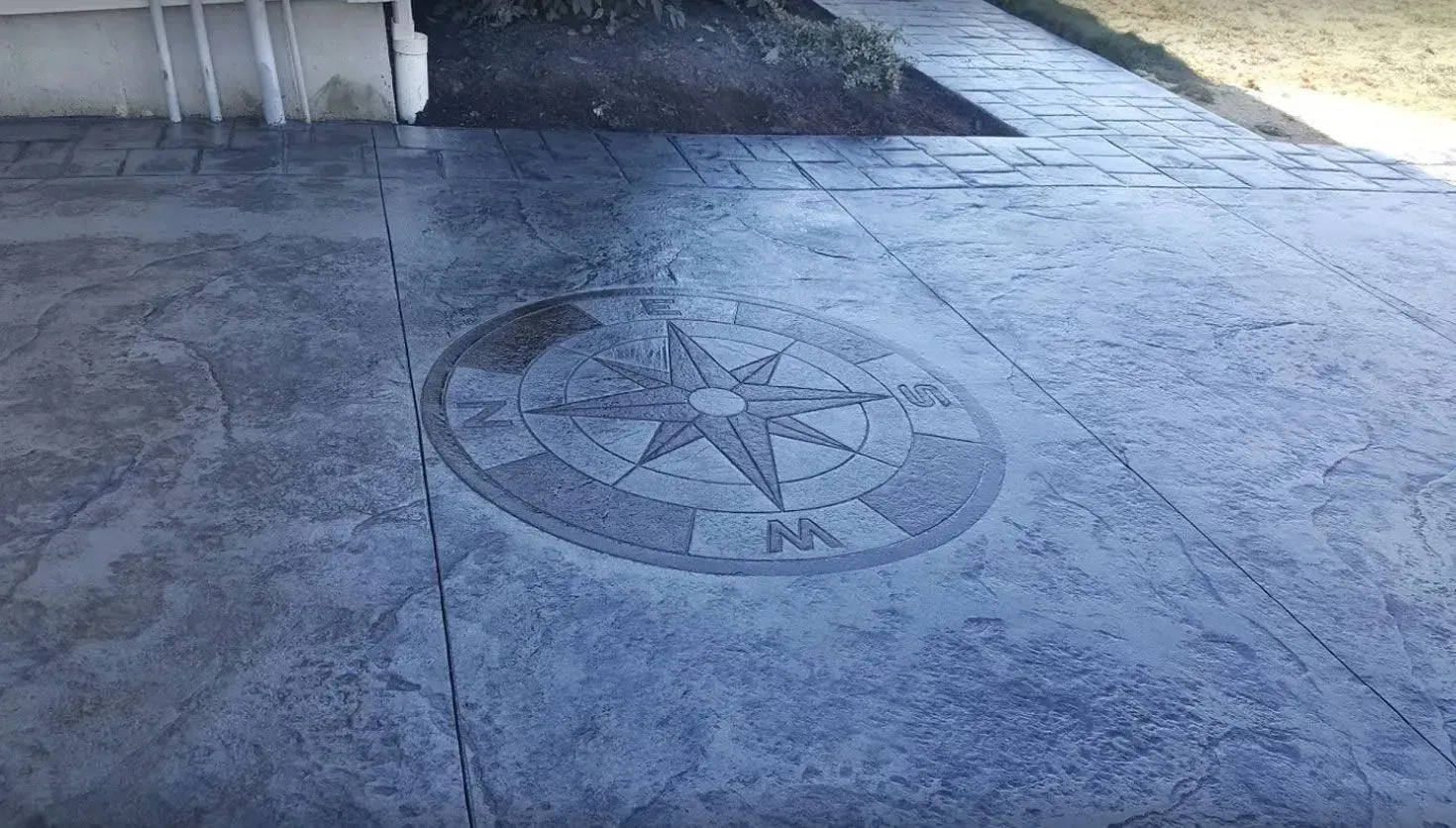 Gray stamped concrete patio featuring a prominent circular compass rose design in the center.