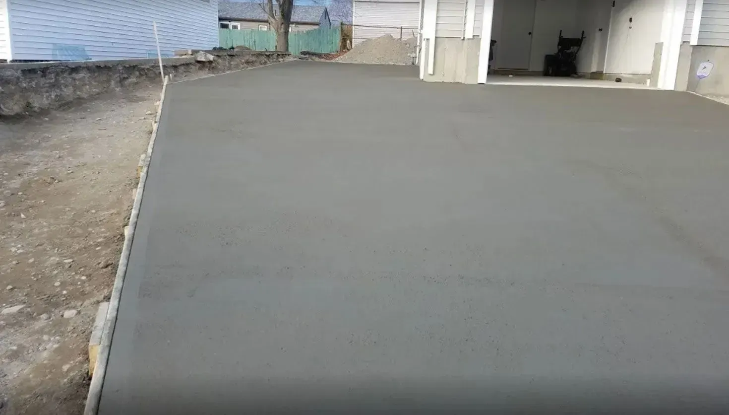 Newly poured smooth gray concrete driveway slab extending from a residential garage.