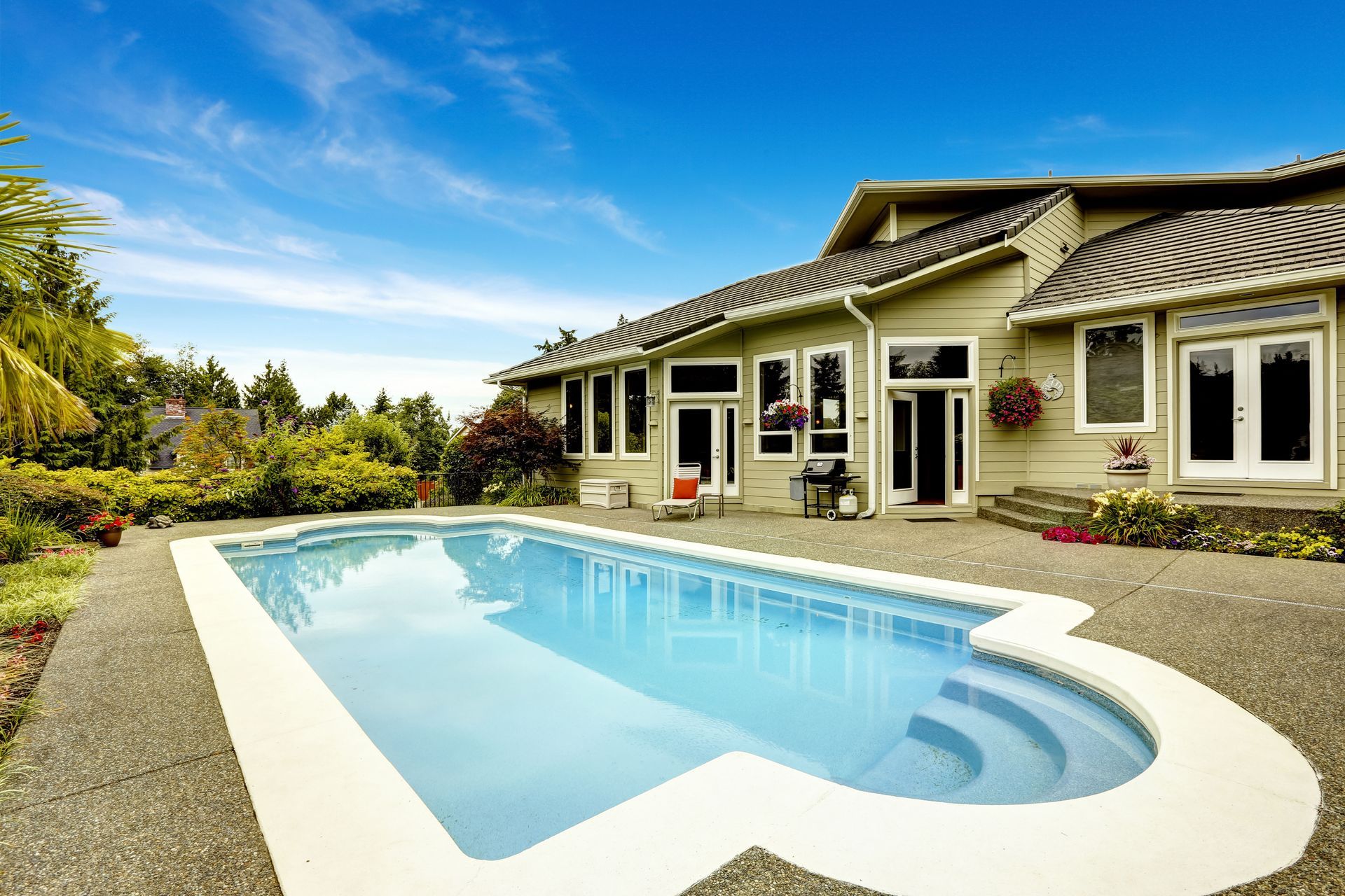 Swimming pool in front of a house with blue sky.