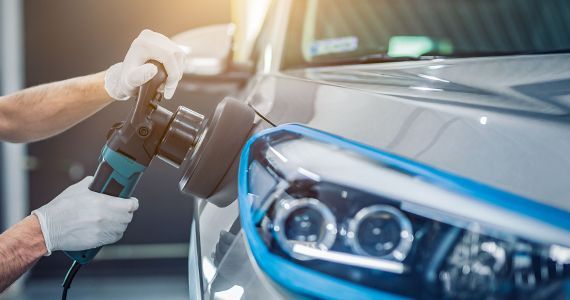 A man is polishing a car with a machine.