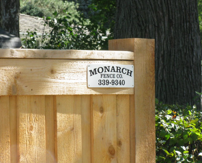 A wooden fence post featuring a white company sign that reads 