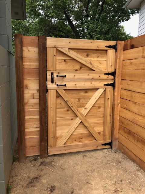 A wooden gate with a diagonal brace and X-frame design, installed between two sections of a matching wood fence.