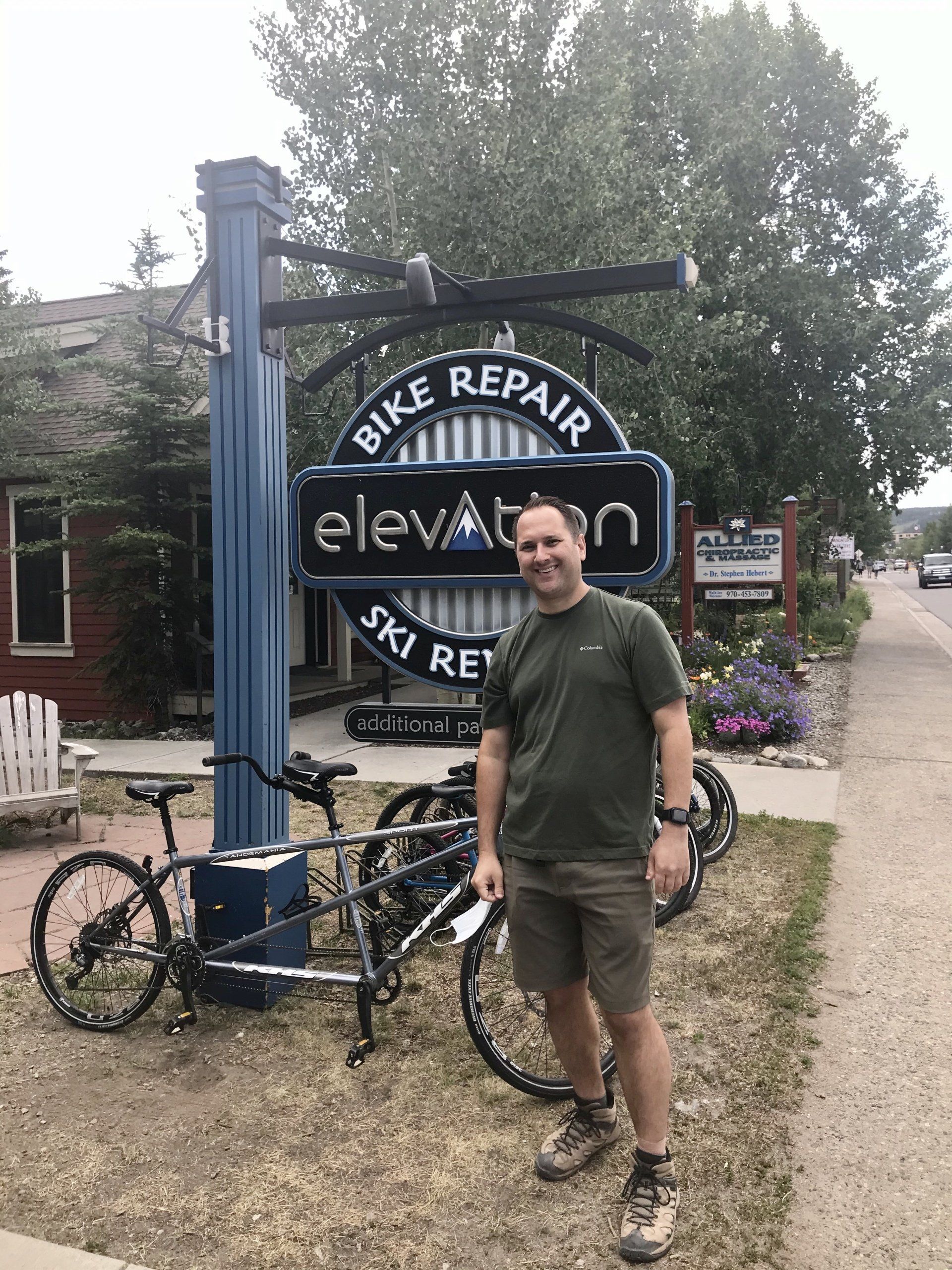 Elevation Ski & Bike owner in front of sign.