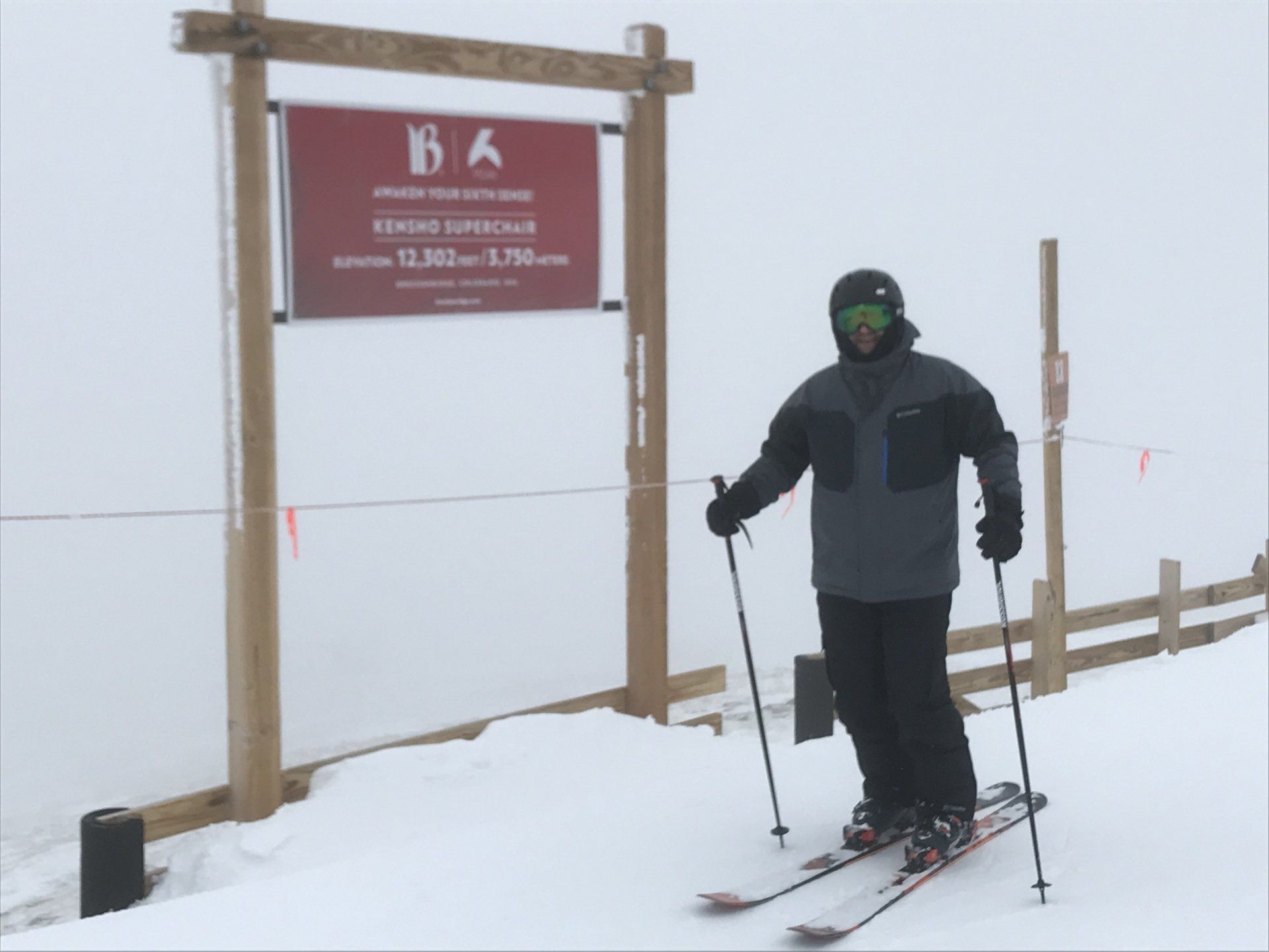 A skier stands in front of a sign that says b6