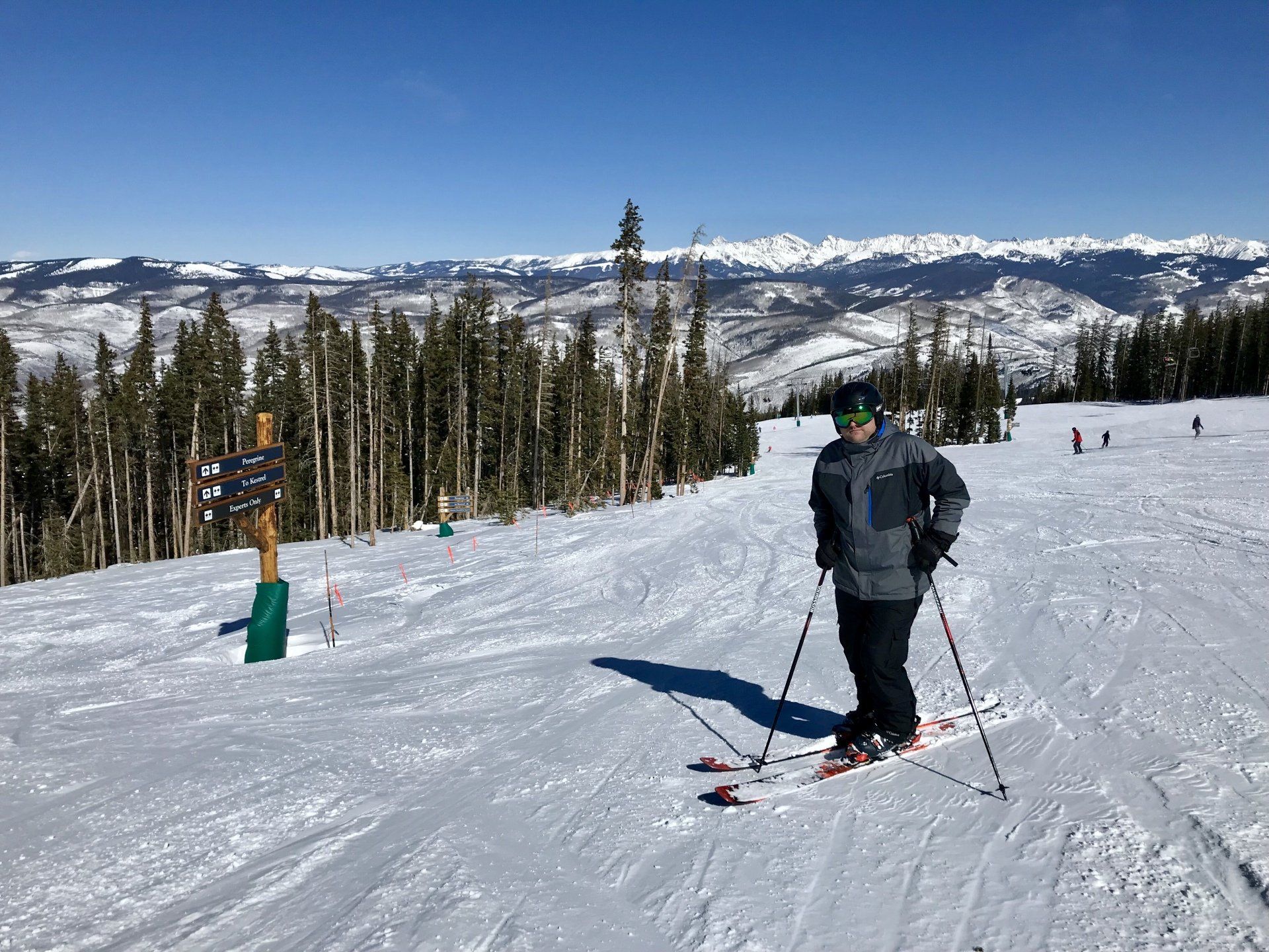 A man is standing on top of a snow covered ski slope.