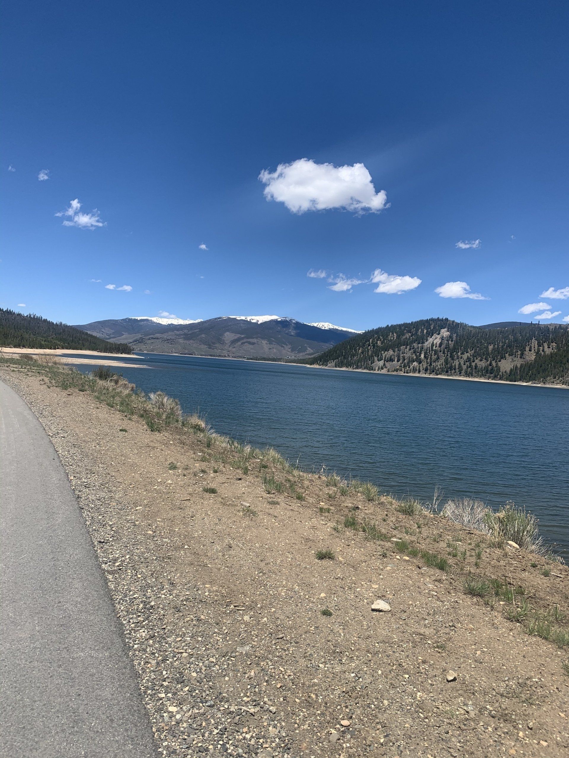 A lake with mountains in the background and a road in the foreground.