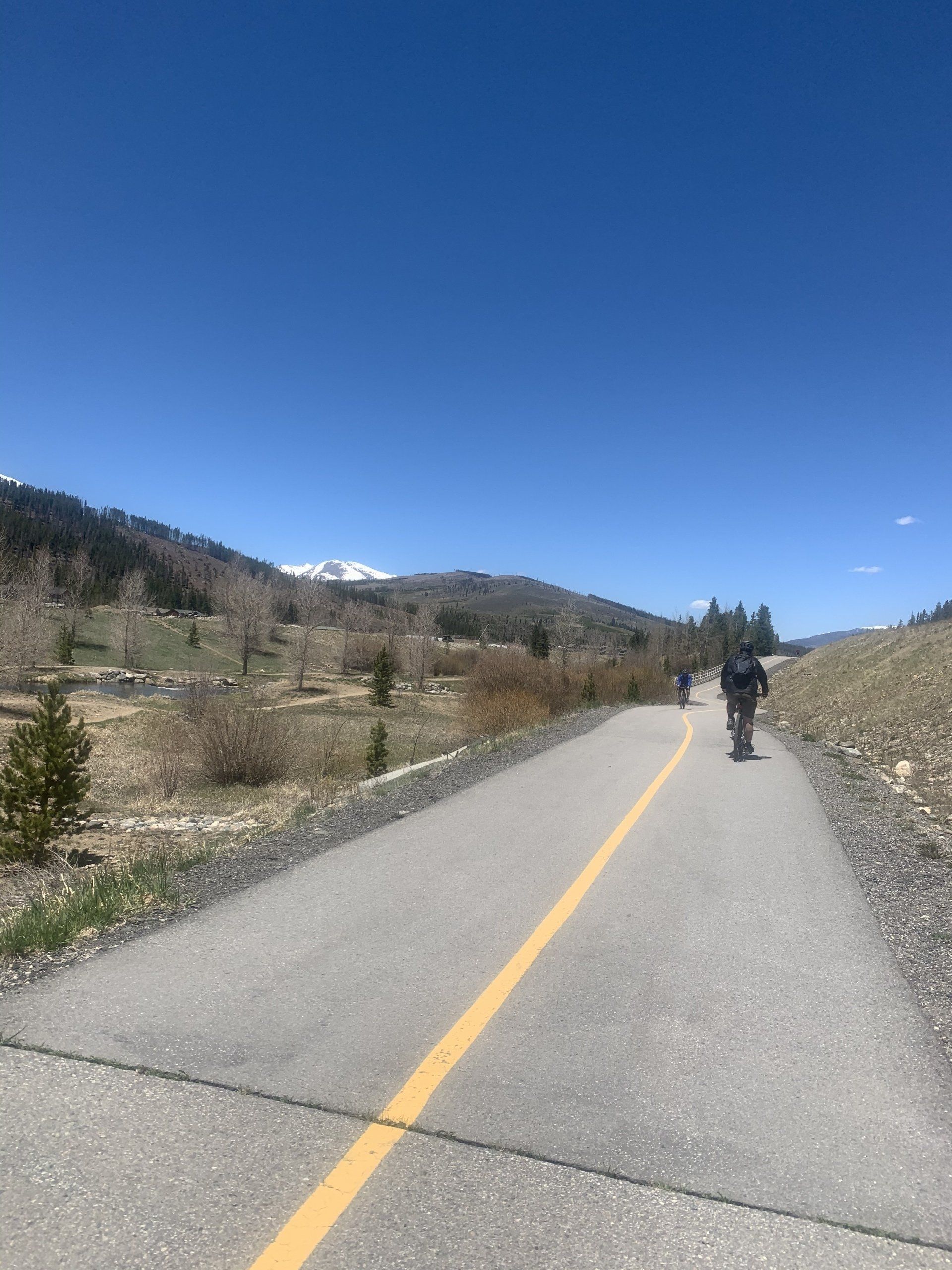 A person is riding a bike down a road with mountains in the background.