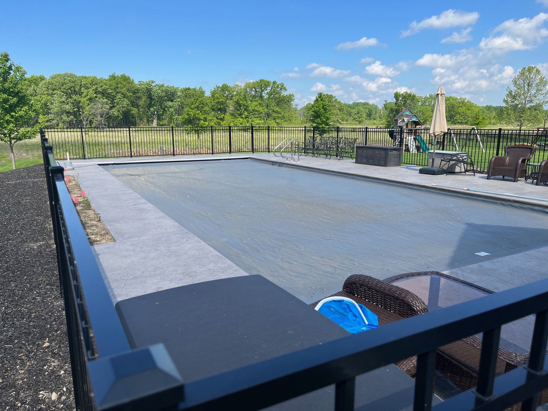 A large swimming pool is surrounded by a black fence.
