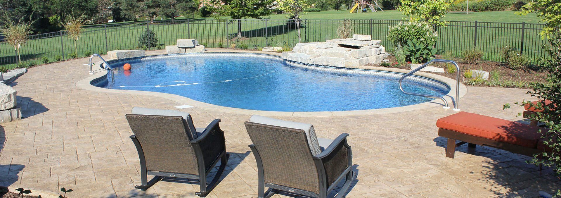 Two chairs are sitting on a patio next to a large swimming pool.