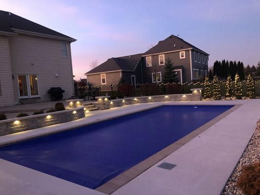 A large swimming pool with a house in the background