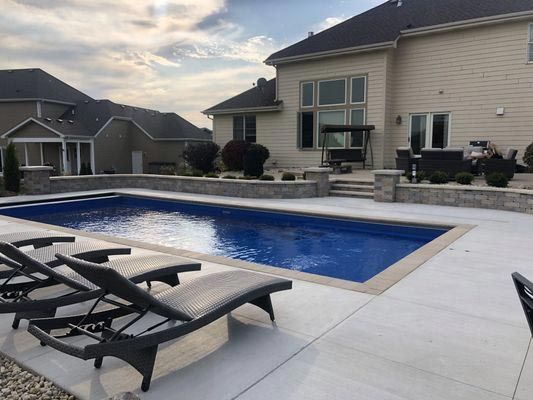 There is a large swimming pool in the backyard of a house.