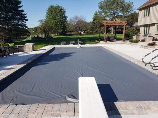 A large swimming pool with a black cover on it