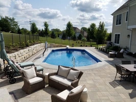 A large swimming pool is in the backyard of a house