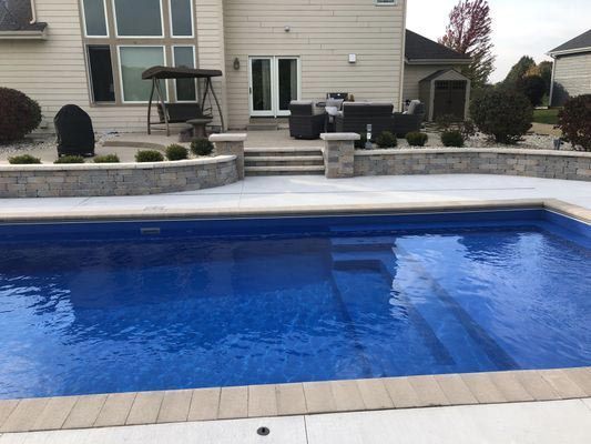A large blue swimming pool is in the backyard of a house.