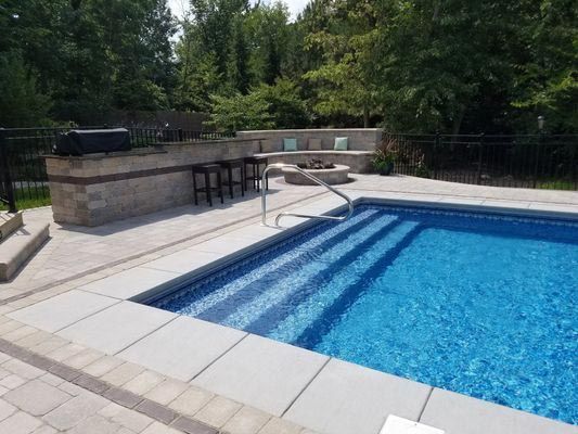 There is a large swimming pool with stairs leading to it.