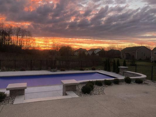 A large swimming pool with a sunset in the background.