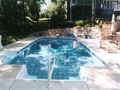 A large swimming pool with a house in the background