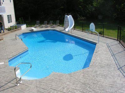 A large swimming pool with a slide and a basketball hoop in the backyard.
