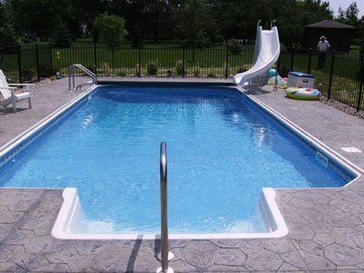 A large swimming pool with a slide in the backyard.