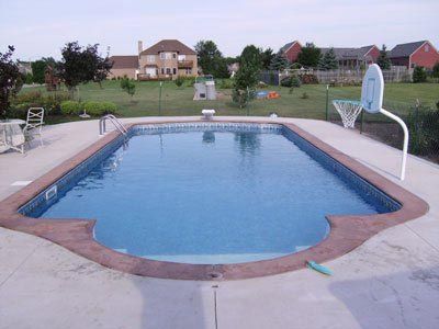A large swimming pool with a basketball hoop in the backyard