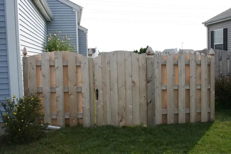 A wooden fence with a gate in front of a house