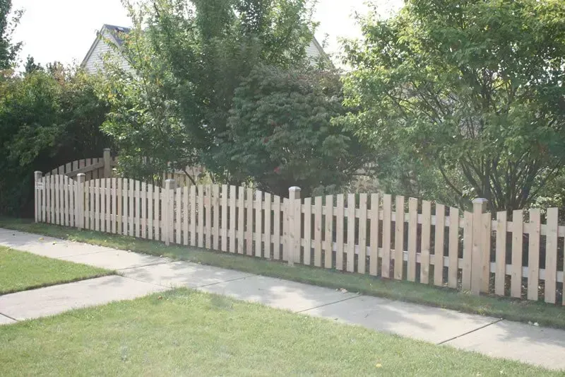 A white picket fence along a sidewalk in front of a house