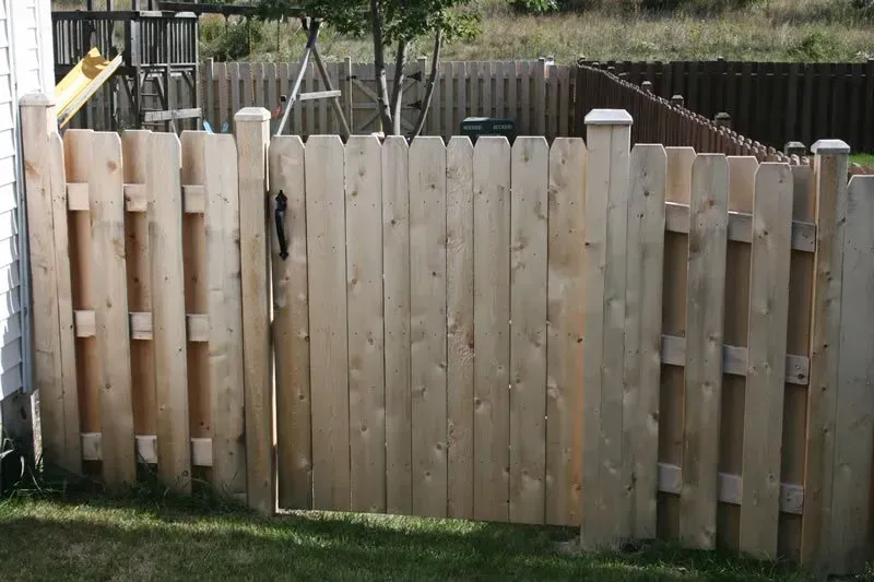 A wooden fence with a swing set in the background