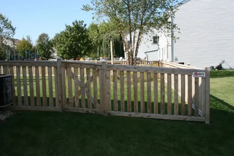 A wooden fence with a gate in the backyard of a house