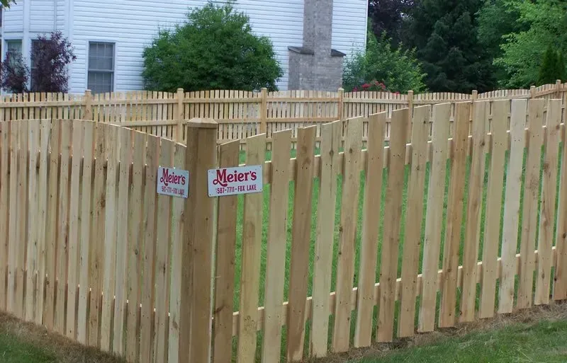 A wooden picket fence is in front of a house.