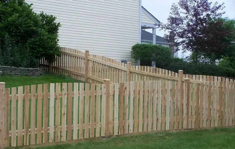 A wooden picket fence is in front of a house