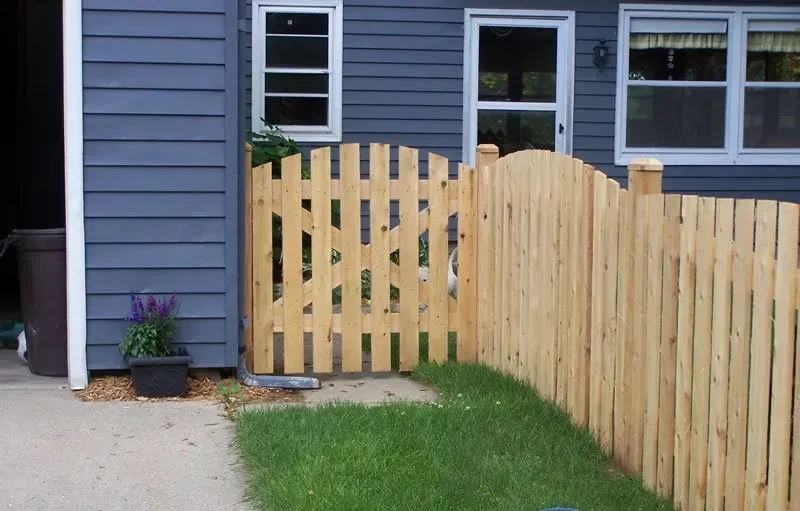 A wooden fence with a gate in front of a house