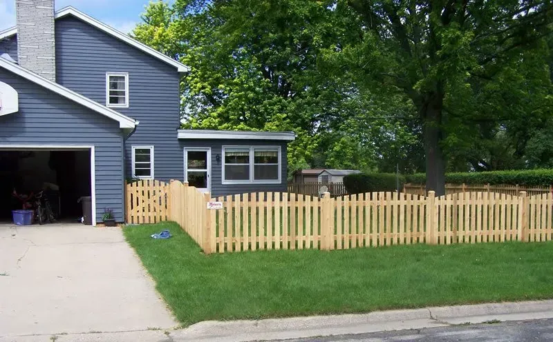 A blue house with a wooden picket fence in front of it