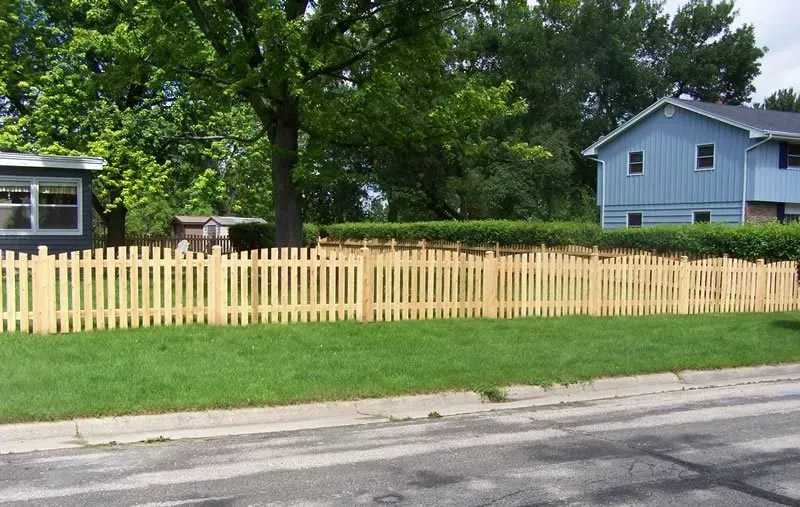 A wooden picket fence with a blue house in the background