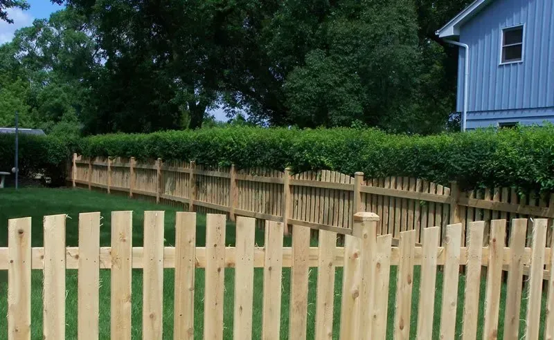 A wooden picket fence in front of a blue house