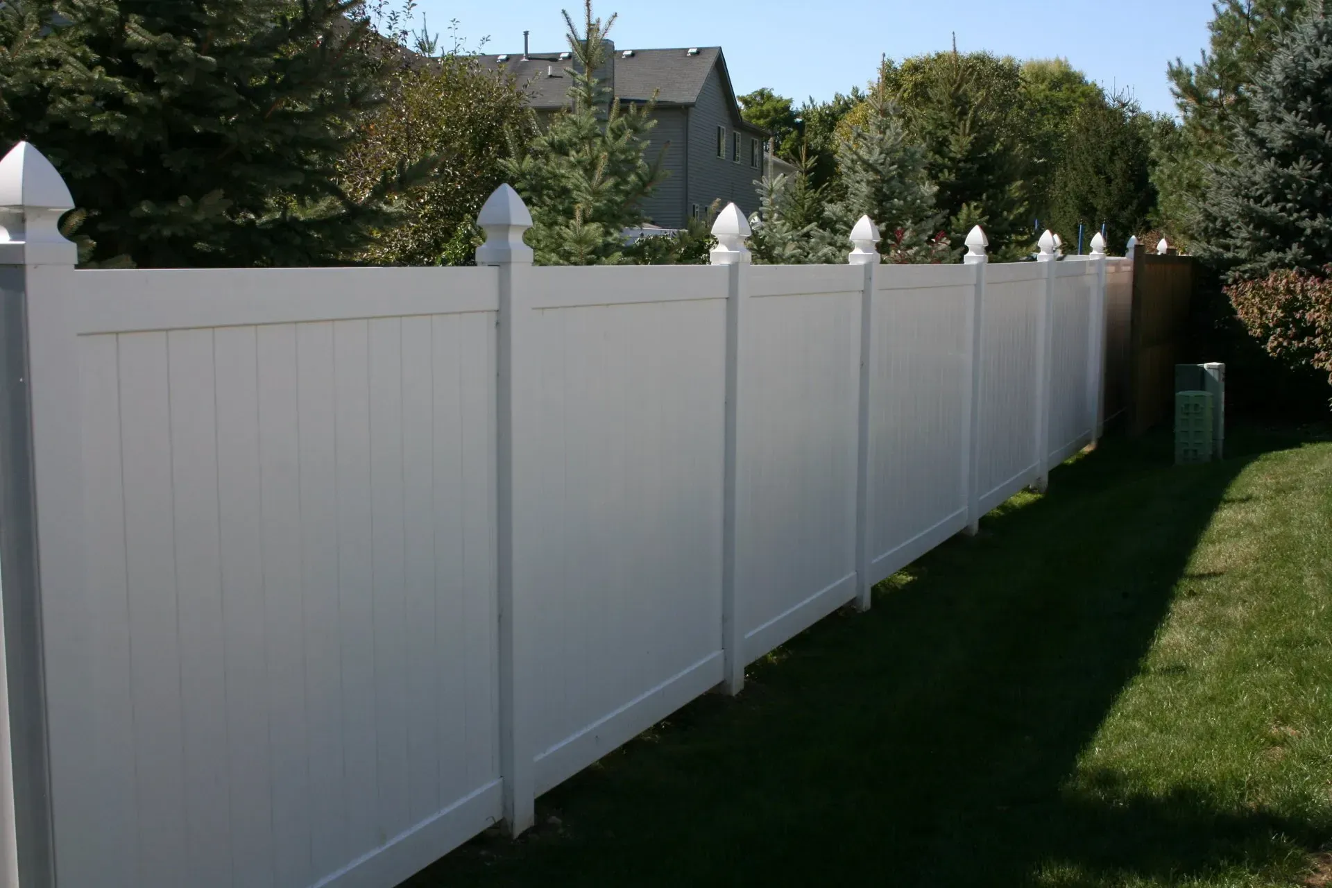 A white fence surrounds a lush green yard