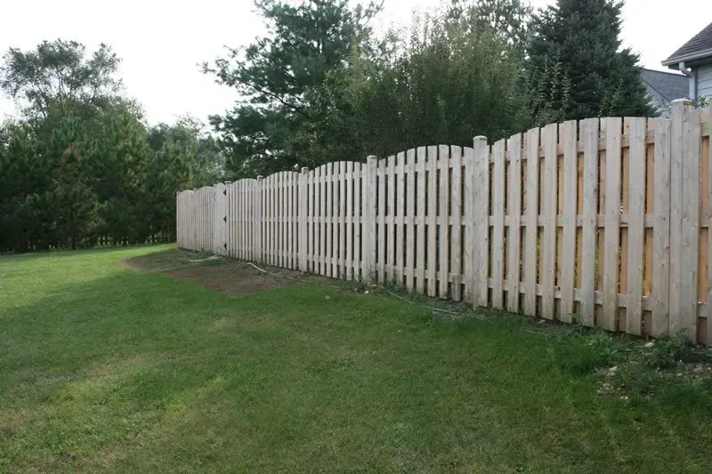 A white picket fence surrounds a lush green field.