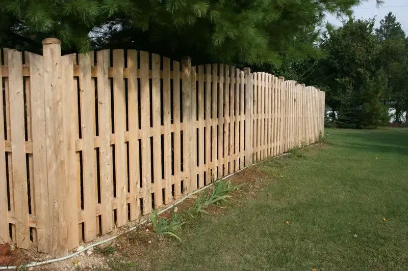 A wooden picket fence surrounds a lush green yard.