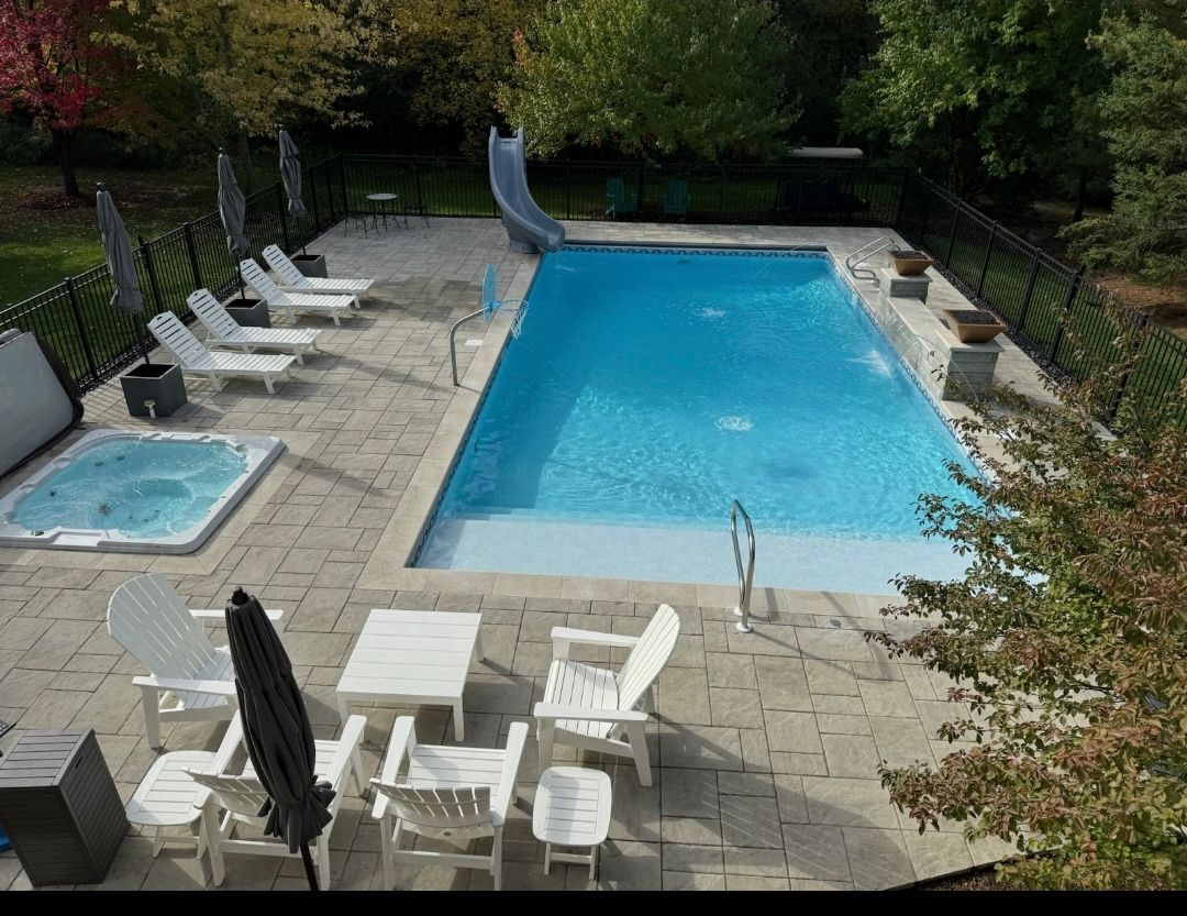 An aerial view of a large swimming pool surrounded by chairs and a hot tub.