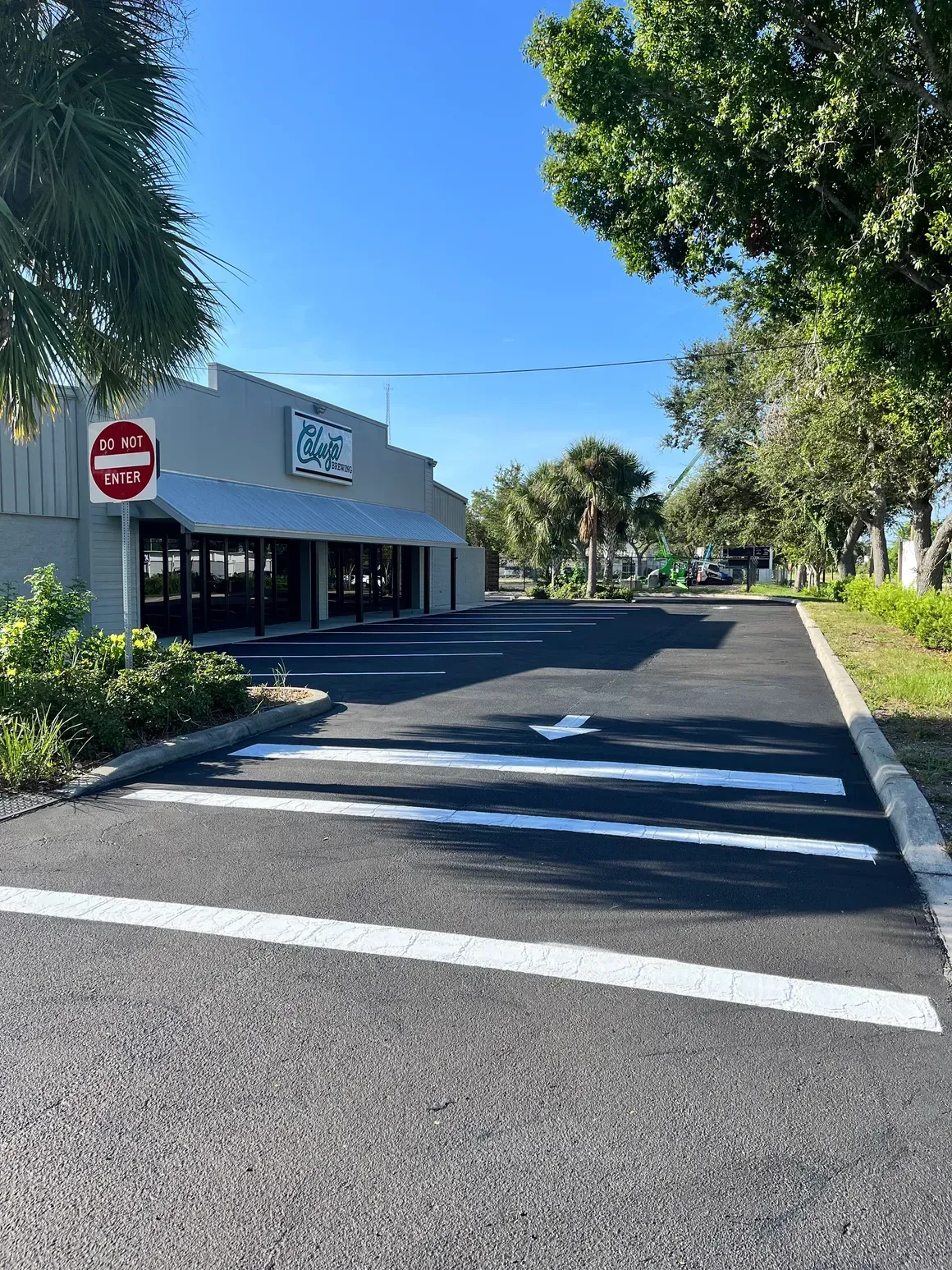 Quiet street beside a white storefront with a red stop sign and crosswalk under clear blue sky
