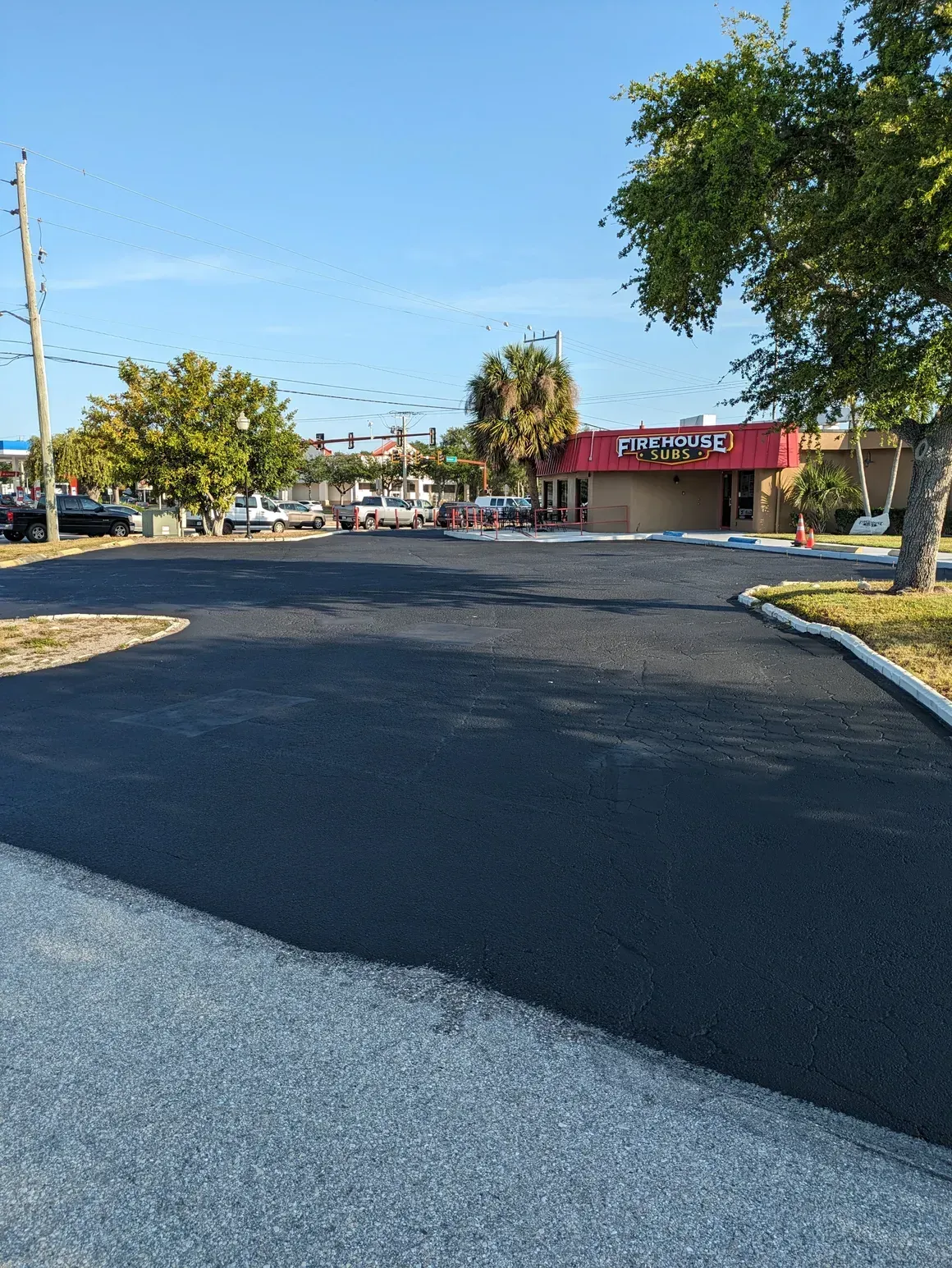 Freshly paved parking lot leading to a low red-roofed building on a sunny day